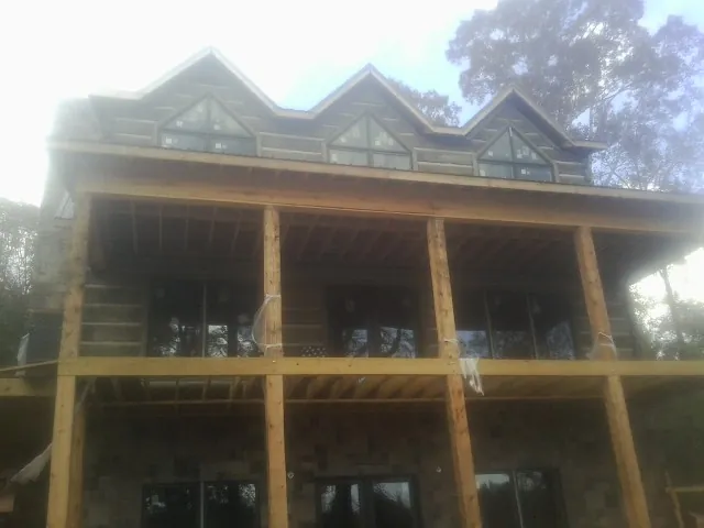 Dormers and porch framing on a large log home under construction — Roof Coating work by our crew in East Lynn
