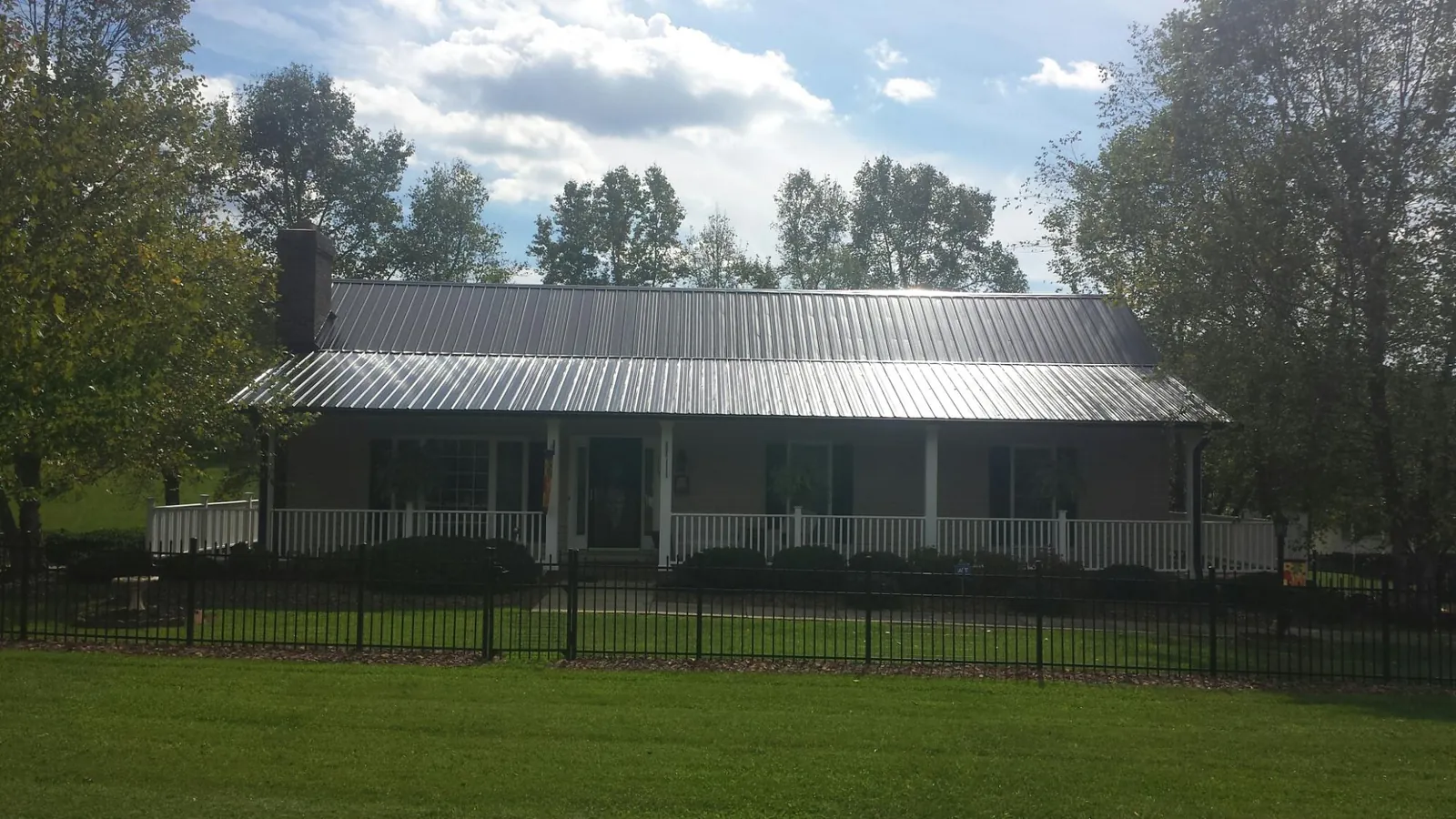 Gray metal roof on a brick ranch with a full width front porch — Gutter Guard Installation work by our crew in East Lynn
