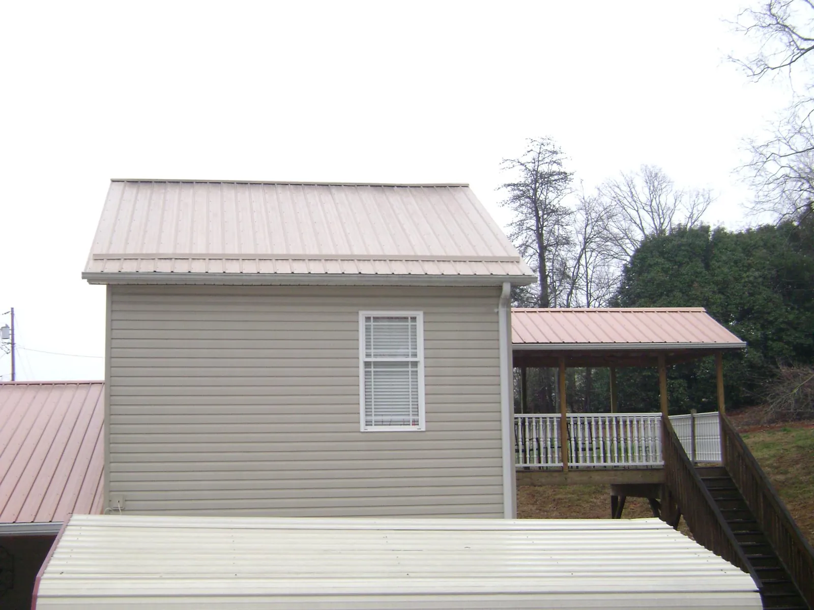 Tan metal roofs on a two story addition and attached porch, from a Roof Replacement job in East Lynn