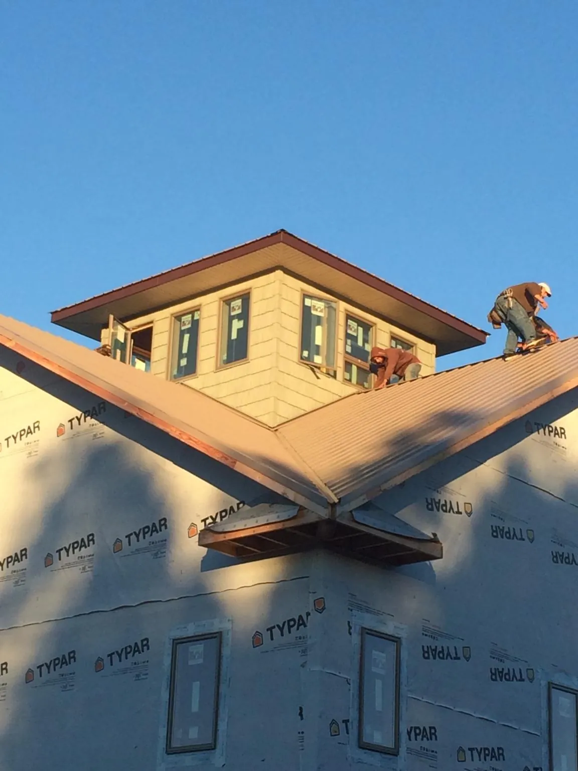 Roofers working around a rooftop cupola on a new metal roof at sunset — Roof Waterproofing in East Lynn by Roofing Brothers